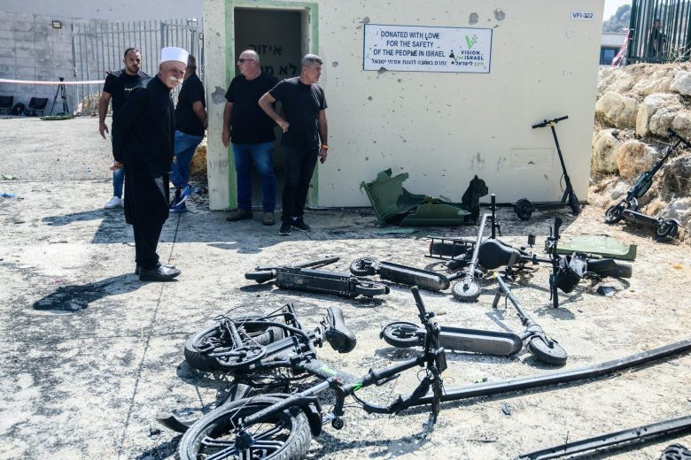 Men look upon the charred remains of scooters and bicycles.