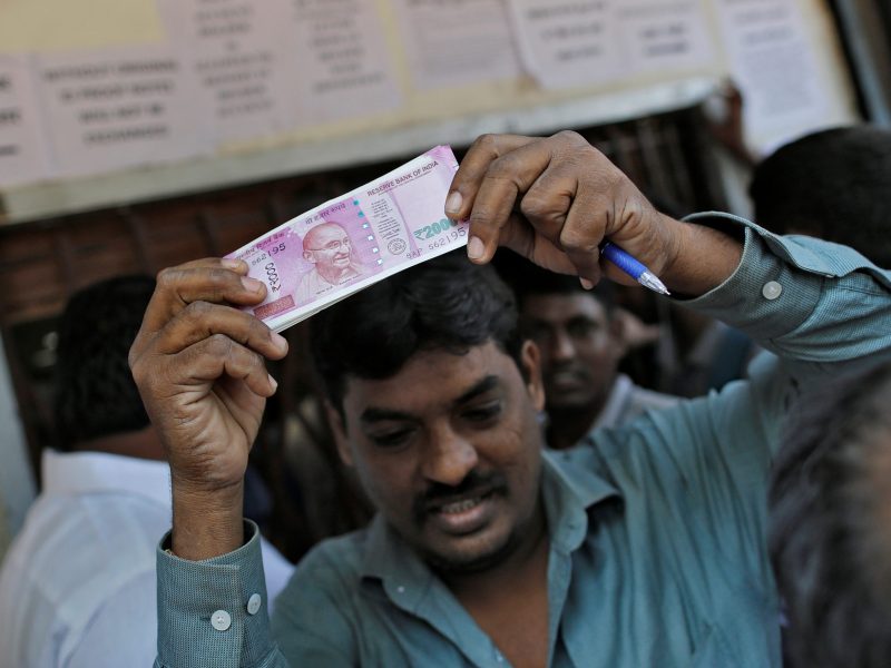 A man holds 2000 Indian rupees notes aloft outside a bank in Mumbai. Photo: Reuters